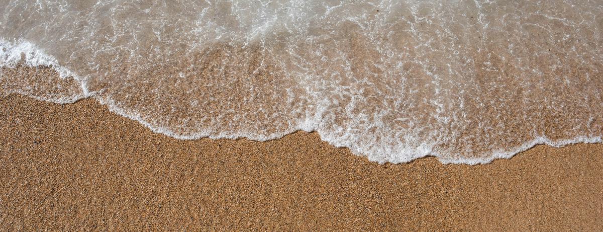 The ocean water washing up on a sandy beach