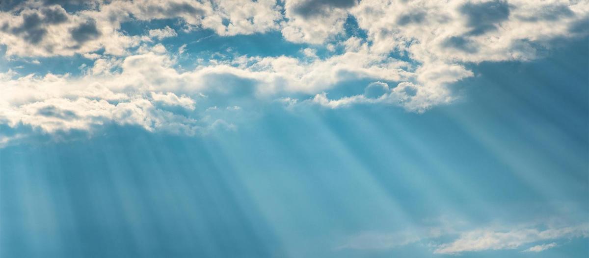 a bright blue sky with puffy clouds and rays of sun beaming down