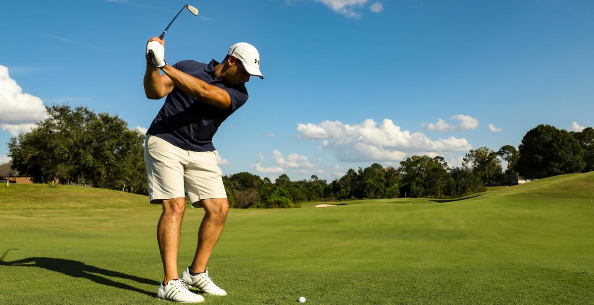 A golfer swinging on a green course