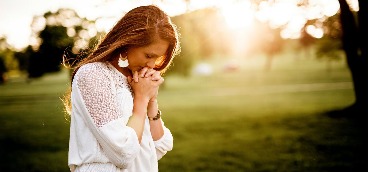Blonde woman with her head bowed in prayer