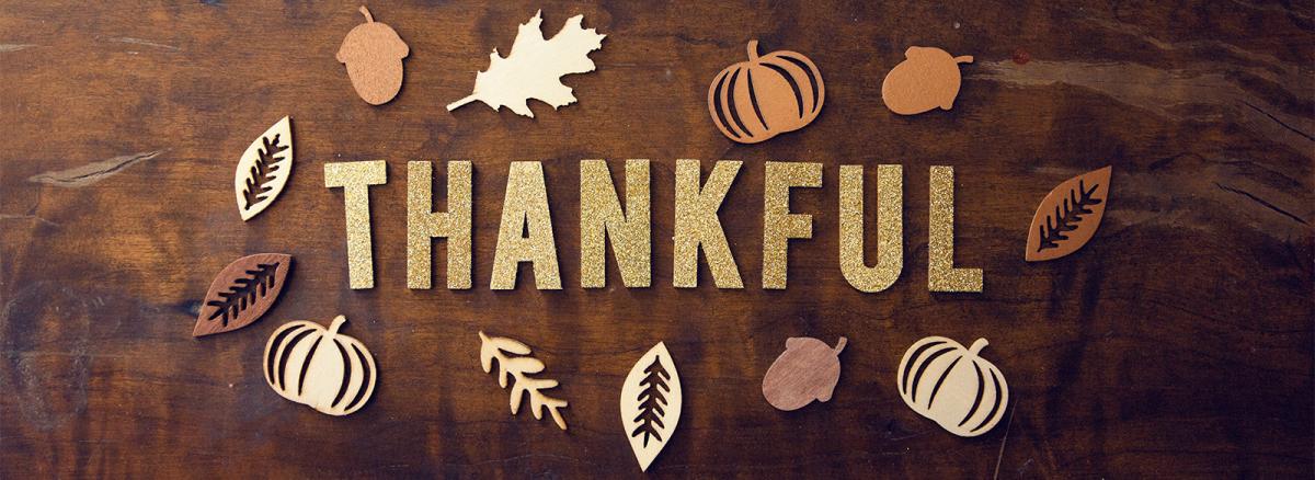 The word Thankful on a wooden background surrounded by leaf cutouts